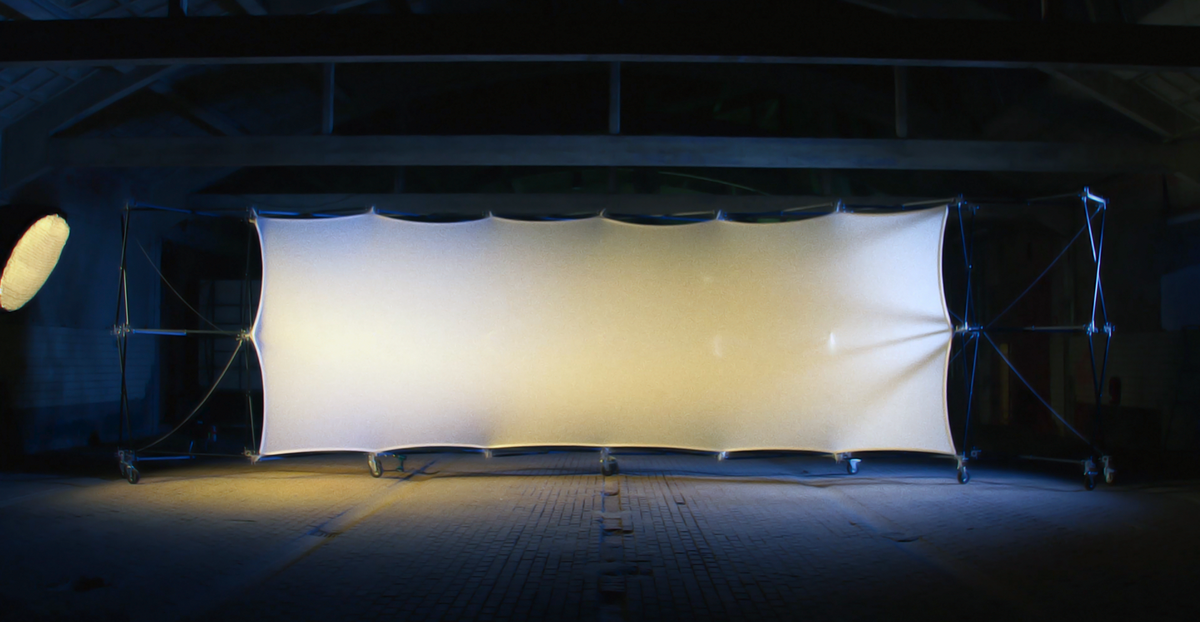 Konligo Luno Wall modular structure with stretched white illuminated fabric panel set up indoors for dramatic lighting effect, now available on MTN SHOP US.