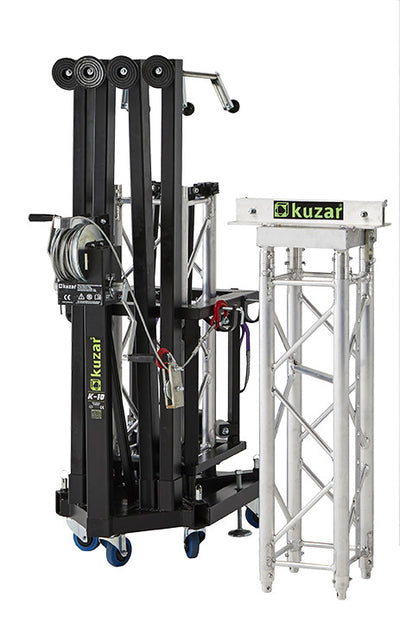 Compact folded view of the Kuzar K-10 tower lifting base on swivel wheels next to a truss section, optimized for space-saving storage and European transport.