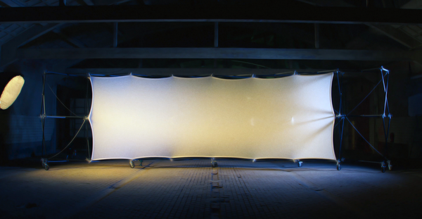 Konligo Luno Wall modular structure with stretched white illuminated fabric panel set up indoors for dramatic lighting effect, now available on MTN SHOP US.